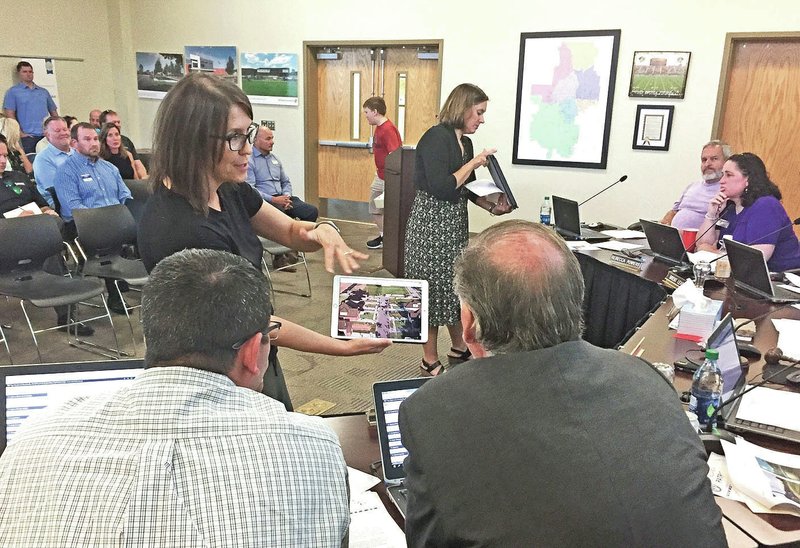 NWA Democrat-Gazette/DAVE PEROZEK Bentonville School Board members Willie Cowgur (left) and Joe Quinn watch Tuesday as Sara McKay shows them a video of traffic in the area of the Lochmoor Club subdivision. McKay and other Lochmoor Club residents attended the meeting to request the School District reverse a decision eliminating school bus service to the neighborhood.