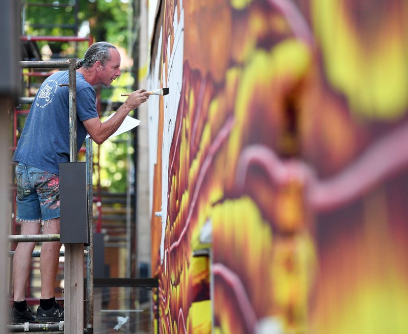 Eugene Sargent paints a mural Wednesday on the side of the Fenix Gallery in the alley west of Arvest Bank on the north side of Fayetteville's square. Sargent is working with Octavio Logo on the mural that will have three-dimensional elements and feature a warrior named Athena who carries a paint brush and palette to signify the power of art. NWA Democrat-Gazette/J.T. WAMPLER