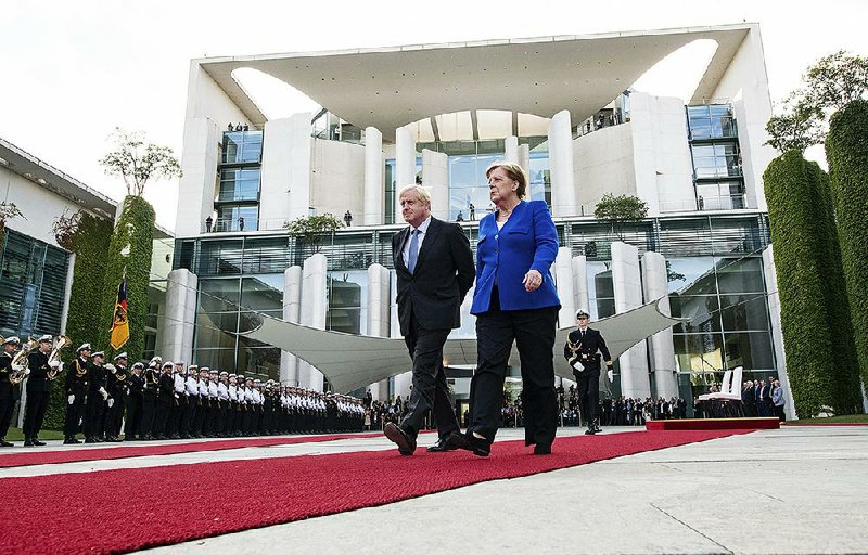 British Prime Minister Boris Johnson and Germany’s Chancellor Angela Merkel walk the red carpet Wednesday during a welcome ceremony in Berlin. Merkel says she plans to discuss how Britain’s exit from the European Union can be “as frictionless as possible.” 