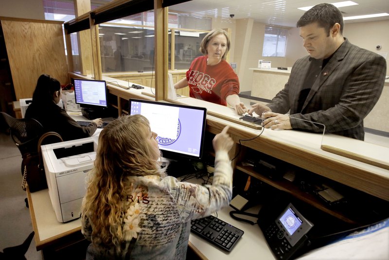 FILE — From left: Myra Martinez, deputy assessor, Jerri Cloud, deputy assessor, and Lea Rochester, chief deputy personal property, test a signature device with Russell Hill, Washington County tax assessor, at a Washington County Assessor office located inside the State Revenue Office and Department of Motor Vehicles in Fayetteville in this Jan. 8 2016 file photo.