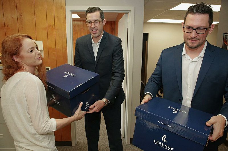 Ben Elder (center), an attorney for Cherokee Nation Businesses of Oklahoma, hands Arkansas Racing Commission executive assistant Nikki Langston (left) a box of documents Thursday in Little Rock as he and another attorney filed the group’s new application for a casino license in Pope County. 