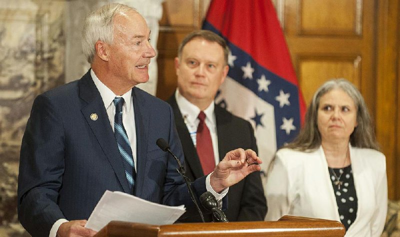 Gov. Asa Hutchinson (left) speaks during a news conference Wednesday at the state Capitol to announce a new resource for Arkansans suffering with mental-health and substance-abuse issues. Listening is Jay Hill, director of the state Department of Human Services’ division of Aging, Adult, & Behavioral Health Services. 