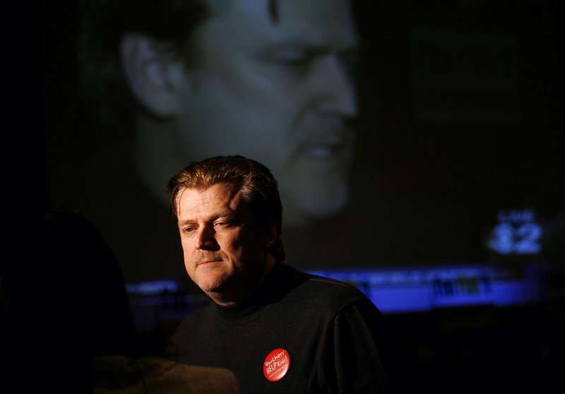 FILE - In this Nov. 6, 2007, file photo Patrick Byrne, President and CEO of Overstock.com is reflected on a large television screen while being interviewed at the headquarters for supporters of school vouchers in Salt Lake City. Byrne has resigned, saying he&#x2019;d become &#x201c;far too controversial&#x201d; to helm the e-commerce company known for selling discounted sofas and jewelry. Bryne, who founded the online discount retailer 20 years ago, said Thursday, Aug. 22, 2019, that was &#x201c;in the sad position&#x201d; of having to step down. (AP Photo/Steve C. Wilson)