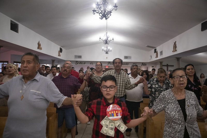 The New York Times/ CALLA KESSLER Parishioners hold hands in prayer during a Mass Aug. 11 at El Buen Pastor Mission on the outskirts of El Paso, Texas, as they honor the victims of the El Paso mass shooting.