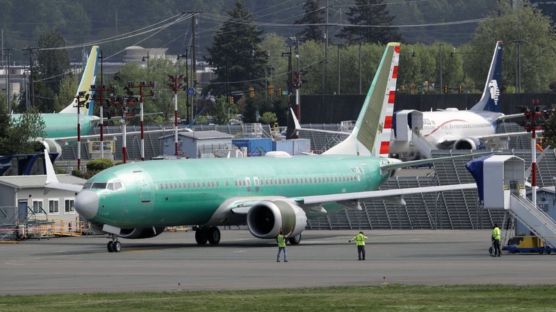 In this Wednesday, May 8, 2019 file photo, workers stand near a Boeing 737 MAX 8 jetliner being built for American Airlines prior to a test flight in Renton, Wash. Federal safety officials are recruiting pilots from airlines around the world to test changes that Boeing is making in flight-control software on the grounded 737 Max jet, according to two people briefed on the situation (AP Photo/Ted S. Warren, File)
