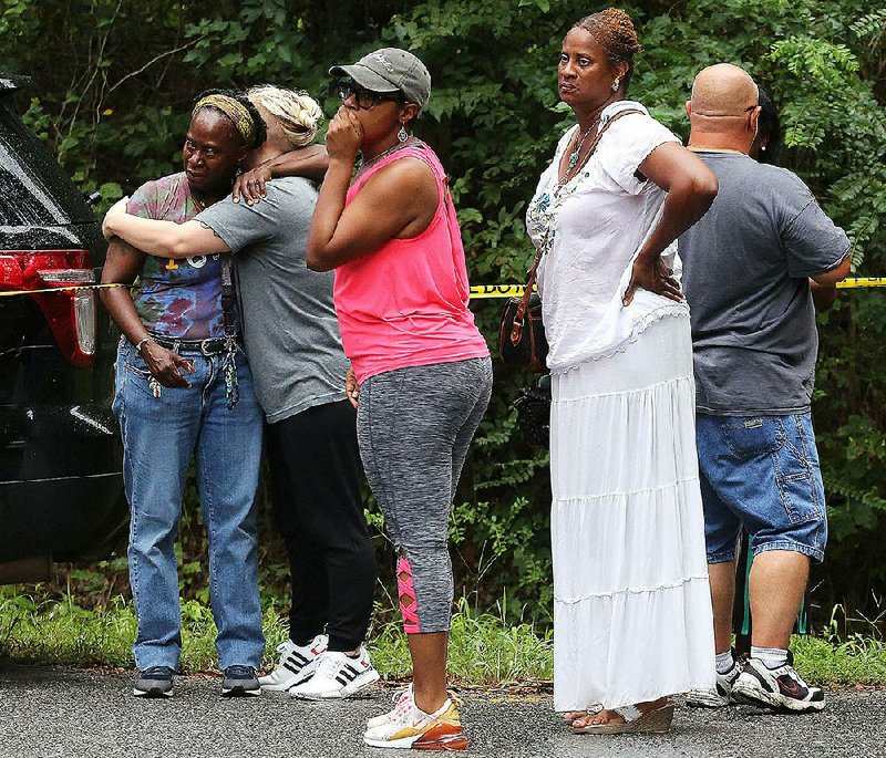 Relatives and friends look on Saturday as Pulaski County sheriff’s deputies investigate the beating death of a Sweet Home man. The man’s son has been arrested in the case, deputies said. 