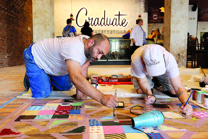 Ben Foch (left) and Paul Minnihan, with Minnihan Painting of Chicago, work Thursday on the hand-painted floor in the lobby of the new Graduate Fayetteville hotel. 
