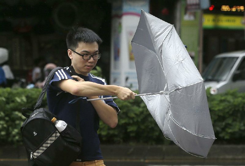 A man in Taipei, Taiwan, struggles with his umbrella against powerful gusts of wind generated Saturday by the tropical storm. 
