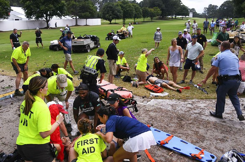 Injured spectators are tended to by first-aid personnel Saturday at the Tour Championship in Atlanta after lightning struck a tree near the 16th tee at East Lake Golf Club. Six were injured. 
