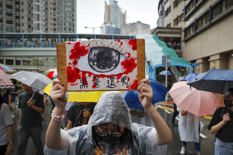 A woman holds a placard that reads "Corrupt police return eyes to the victims" as demonstrators march in the rain in Hong Kong, Sunday, Aug. 25, 2019. Umbrella-carrying protesters took to the streets in the rain Sunday in Hong Kong's latest pro-democracy demonstration, one day after the return of clashes with police who used tear gas to disperse them. (AP Photo/Kin Cheung)