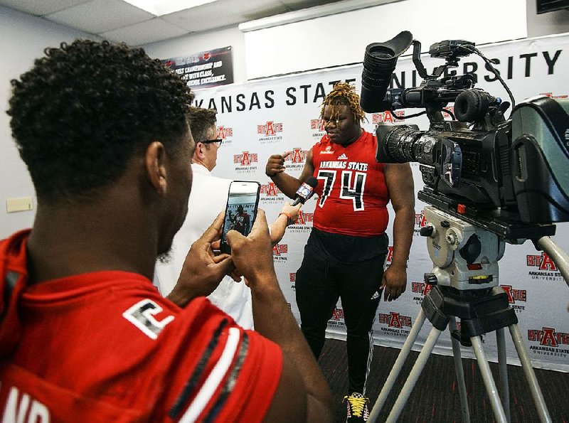 ASU running back Warren Wand snaps a photo of teammate Andre Harris Jr. while he speaks to a reporter during Arkansas State Media Day at the ASU Football Complex in Joneboro Thursday, August 2, 2018.