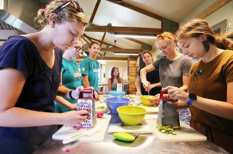 File photo/NWA Democrat-Gazette/DAVID GOTTSCHALK Marissa Dull (left), with FoodCorps, grates a radish Wednesday for a zesty radish cream cheese spread during a facilitator training program in the teaching kitchen at the Apple Seeds Teaching Farm in Fayetteville. The Planning Commission on Monday approved some changes to the nonprofit group's permit to operate.