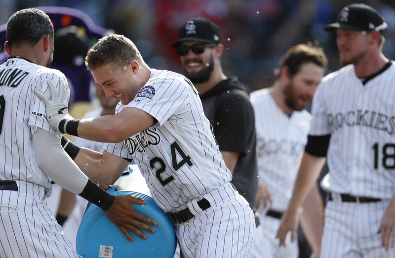Colorado Rockies' Ryan McMahon, center, pushes Ian Desmond after Desmond doused him as he crossed home plate after his two-run walkoff home run off Atlanta Braves relief pitcher Jerry Blevins in the ninth inning of a baseball game Monday, Aug. 26, 2019, in Denver. (AP Photo/David Zalubowski)
