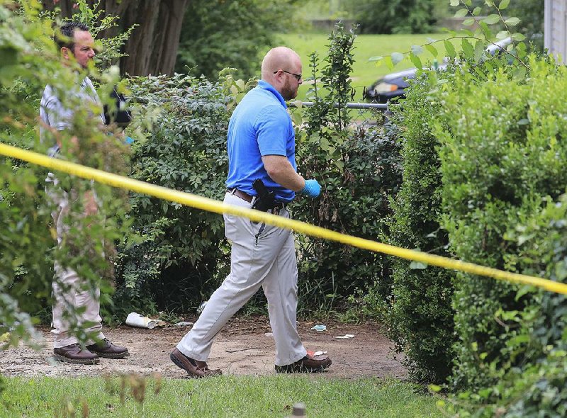 Little Rock police officers investigate a homicide Tuesday at 8017 W. 35th St. where members of the Little Rock Fire Department, responding to a call, found a man fatally shot. 
