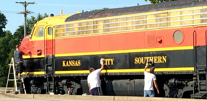 Westside Eagle Observer/SUBMITTED Armed with electric buffers and lots of rubbing compound, a group of local volunteers gives KSC locomotive 73D a much-needed polish job Aug. 17 near the Decatur Depot in Decatur. Kansas City Southern's mainline route from Kansas City to New Orleans lies to the west of the locomotive which once ran on this very track.