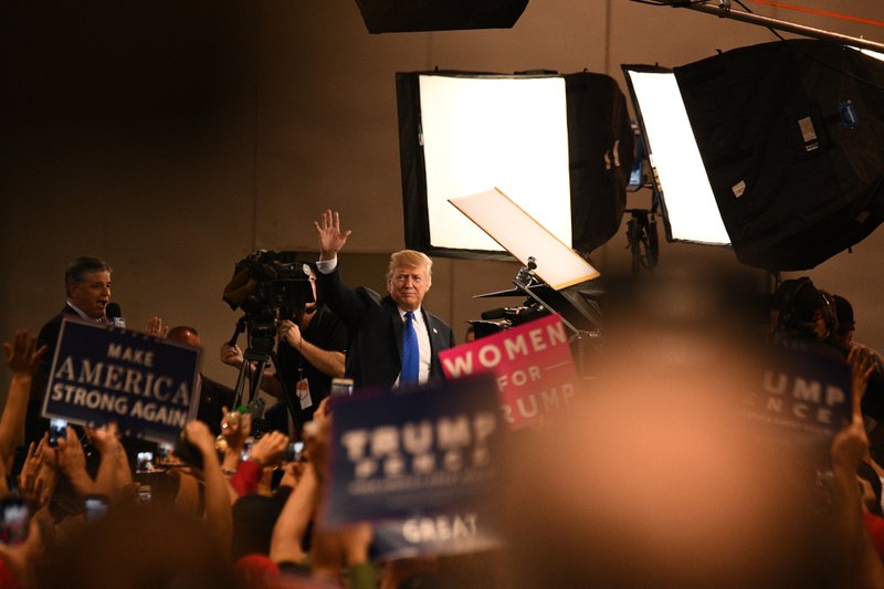 President Donald Trump (center) waves to the audience following an interview with Sean Hannity, host at Fox News (left) at a rally in Las Vegas on Sept. 20, 2018. Bloomberg photo by Bridget Bennett.