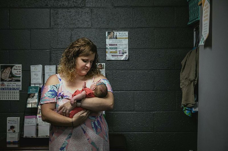 Wendy Ramsey, the director of Options Pregnancy Help Center, holds a 3-week-old while the baby’s mother selects donated items, in Newport, Tenn. 