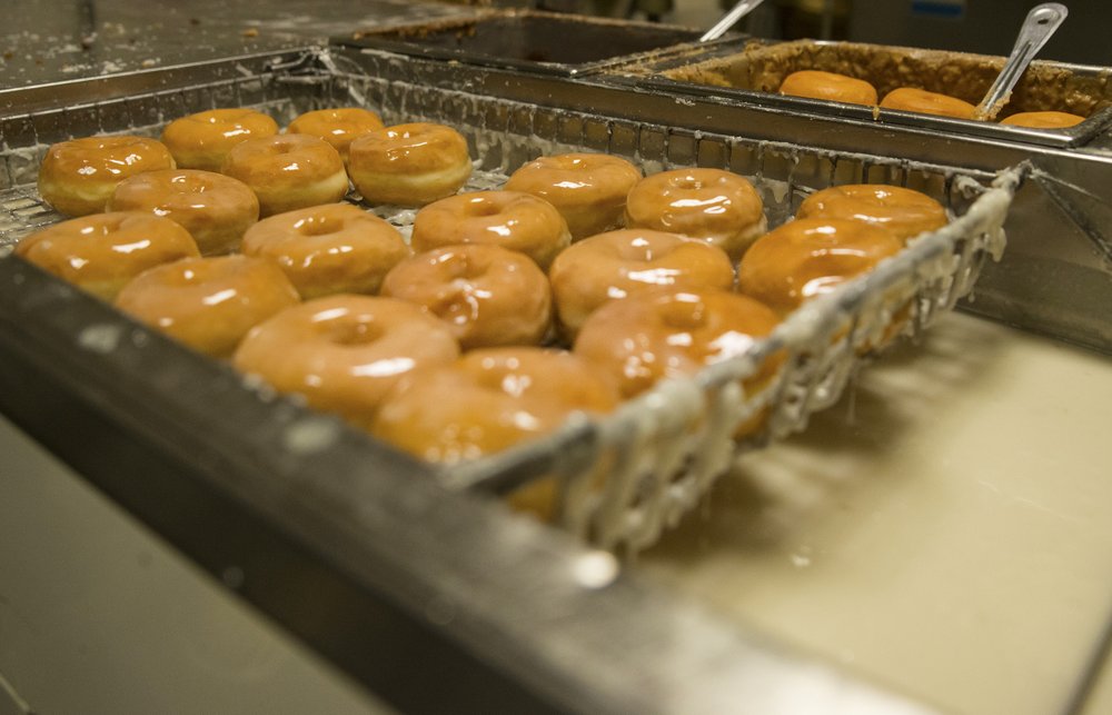 Fresh made spudnuts as they get a coating of glaze. 