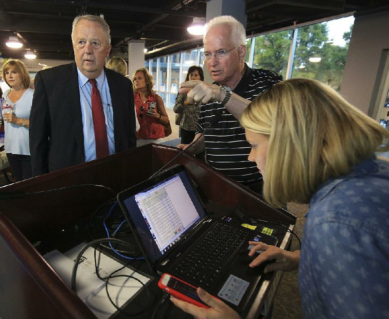 North Little Rock Mayor Joe Smith (left) and North Little Rock Chamber of Commerce President and CEO John Owens watch the returns as Stacy Hamilton posts them Tuesday night at a watch party in North Little Rock for the sales tax increase. 