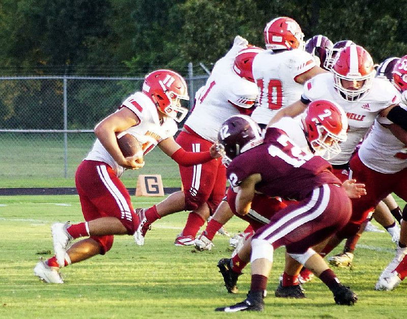 Dardanelle quarterback Jordan Metcalf (left) runs behind his  offensive line Friday during the Sand Lizards’ 17-14 victory over  the Gentry Pioneers in Gentry. 