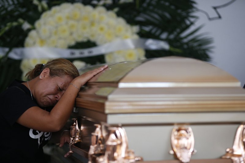 Vanessa Galindo Blas grieves on the coffin that contains the remains of her late husband Erick Hernandez Enriquez, also known as DJ Bengala, who was killed in an attack on the White Horse nightclub where he was DJ'ing, as the family brings his body for burial in the municipal cemetery in Coatzacoalcos, Veracruz state, Mexico, Thursday, Aug. 29, 2019.  (AP Photo/Rebecca Blackwell)