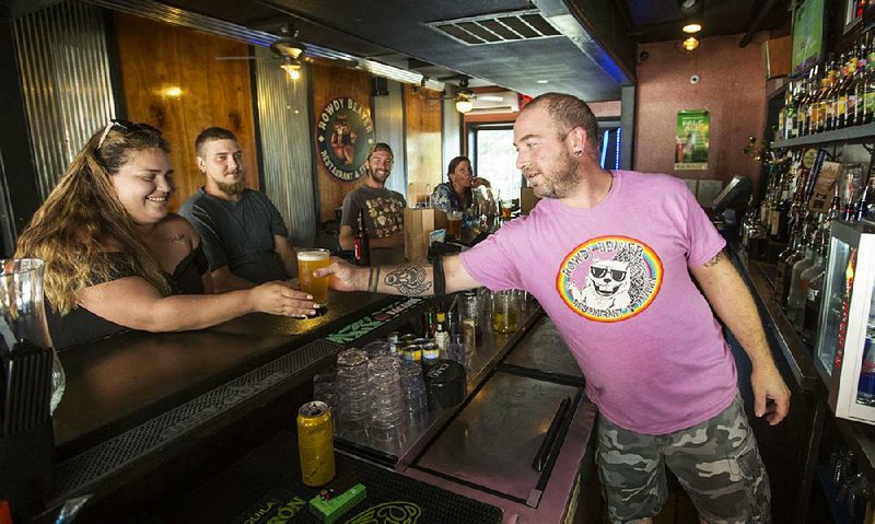 John Gray, a bartender at Rowdy Beaver Den and Store on Spring Street in Eureka Springs, serves a beer Thursday to Stephanie Acosta of New Orleans. A proposed ordinance would authorize the creation of permanent and temporary entertainment districts in the popular tourist town, something some residents oppose. 