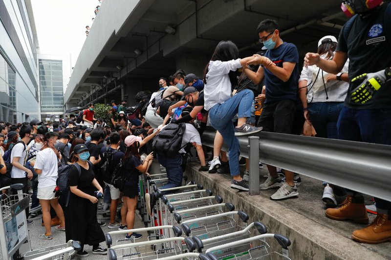 Pro-democracy protestors leave after riot police arrive outside the airport in Hong Kong, Sunday, Sept.1, 2019. Train service to Hong Kong's airport was suspended Sunday as pro-democracy demonstrators gathered there, while protesters outside the British Consulate called on London to grant citizenship to people born in the former colony before its return to China. (AP Photo/Kin Cheung)