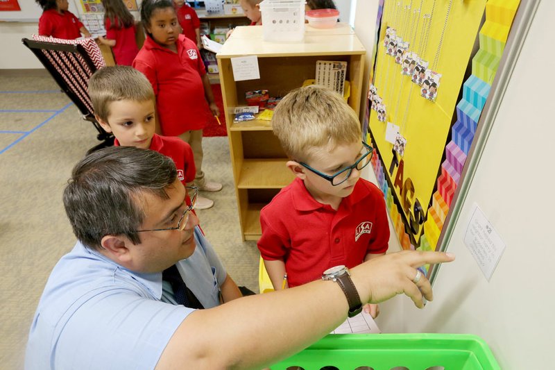 NWA Democrat-Gazette/DAVID GOTTSCHALK Hasan Sazci (from left), Lisa Academy Springdale principal, helps Anthony Grayson and Coen Thompson, both first-graders in Larissa McCraw's classroom, with a social studies scoot project Aug. 16 at the academy in Springdale. The academy is now in the location of the former Ozark Montessori Academy.
