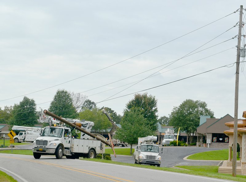 Keith Bryant/The Weekly Vista Carroll Electric trucks haul power poles to replace damaged units near Village Center last Tuesday, Aug. 27. Numerous utility poles were damaged in this part of town, and Carroll Electric spokesperson Nancy Plagge said a total of 105 poles were broken by the storm.
