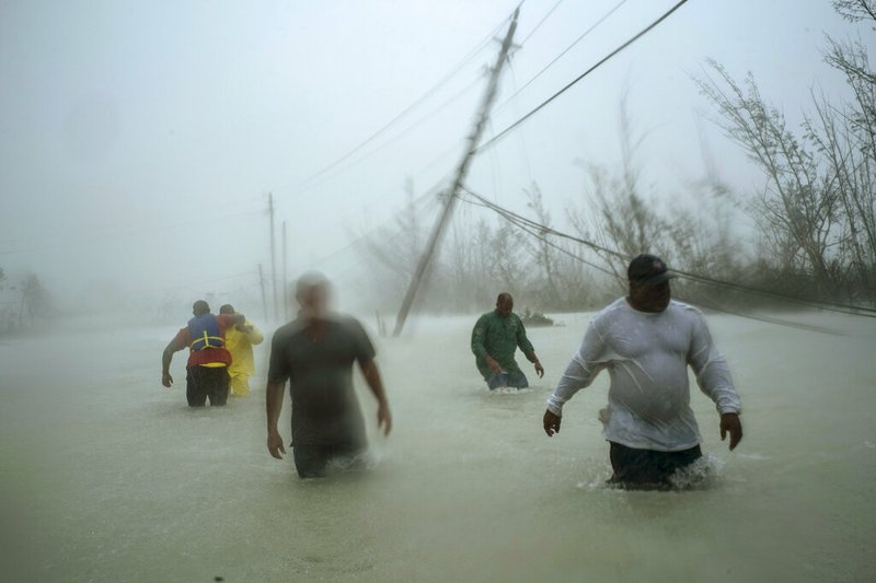 Volunteers walk under the wind and rain from Hurricane Dorian through a flooded road as they work to rescue families near the Causarina bridge in Freeport, Grand Bahama, Bahamas, Tuesday, Sept. 3, 2019. The storm’s punishing winds and muddy brown floodwaters devastated thousands of homes, crippled hospitals and trapped people in attics. (AP Photo/Ramon Espinosa)

