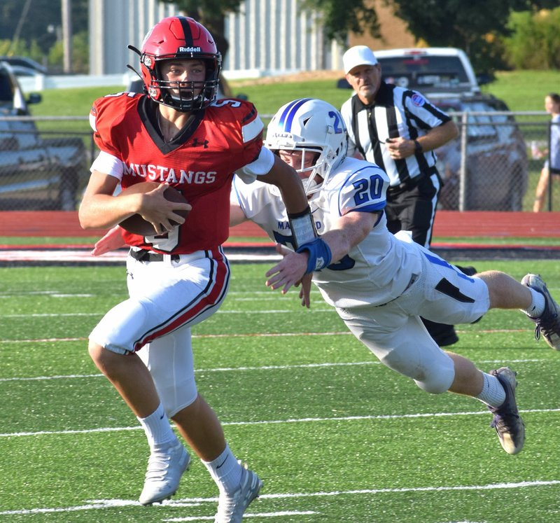 RICK PECK/SPECIAL TO MCDONALD COUNTY PRESS McDonald County junior varsity quarterback Colton Ruddick outruns a Marshfield defender for a short gain in the Mustangs' 28-18 loss in a combined JV/freshman game on Sept. 2 at MCHS.