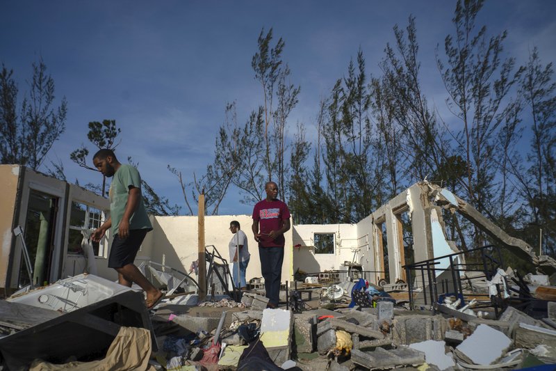 George Bolter, left, and his parents walk through the remains of his home destroyed by Hurricane Dorian in the Pine Bay neighborhood of Freeport, Bahamas, Wednesday, Sept. 4, 2019. Rescuers trying to reach drenched and stunned victims in the Bahamas fanned out across a blasted landscape of smashed and flooded homes Wednesday, while disaster relief organizations rushed to bring in food and medicine. (AP Photo/Ramon Espinosa) story.lead_photo.caption