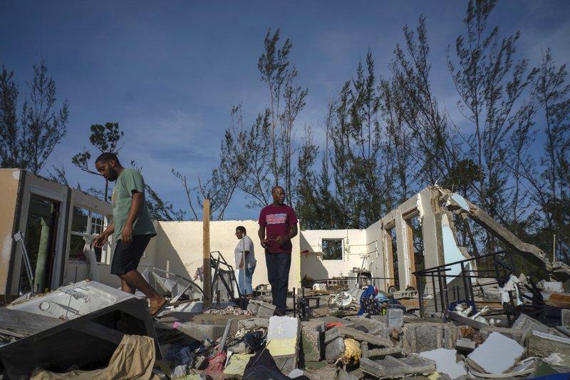 George Bolter, left, and his parents walk through the remains of his home destroyed by Hurricane Dorian in the Pine Bay neighborhood of Freeport, Bahamas, Wednesday, Sept. 4, 2019. Rescuers trying to reach drenched and stunned victims in the Bahamas fanned out across a blasted landscape of smashed and flooded homes Wednesday, while disaster relief organizations rushed to bring in food and medicine. (AP Photo/Ramon Espinosa)