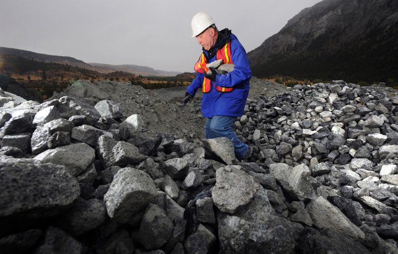 FILE - In this Sept. 2009 file photo, U.S. Geological Survey project geologist Doug Stoeser looks through a huge pile of waste rock from the Stillwater Mine in Nye, Mont. Mine owner Sibanye-Stillwater says it will add around 300 workers in Montana by the end of 2021. (James Woodcock/The Billings Gazette via AP, File)