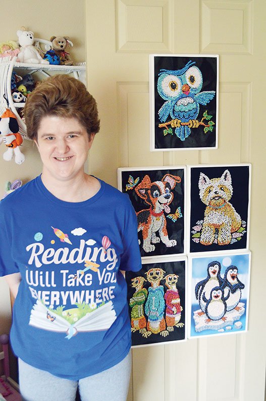 Emily Aldridge, who turns 37 today, stands in her bedroom with some of the sequined crafts she makes. Emily also creates latch-hook pieces. Her work will be on display at Grace United Methodist Church today through Sept. 15. The church is at 1075 Hogan Lane.