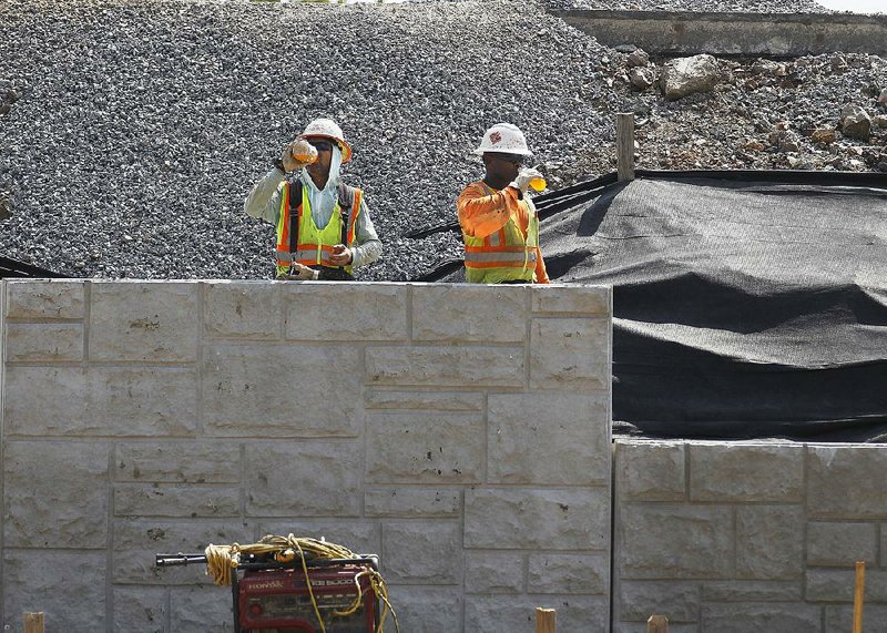 FILE — A pair of construction workers with Manhattan Road and Bridge sip on sports drinks while waiting to put another concrete barrier into place at the Rodney Parham exit on I-630 on Friday, Sept. 6, 2019, in Little Rock.
