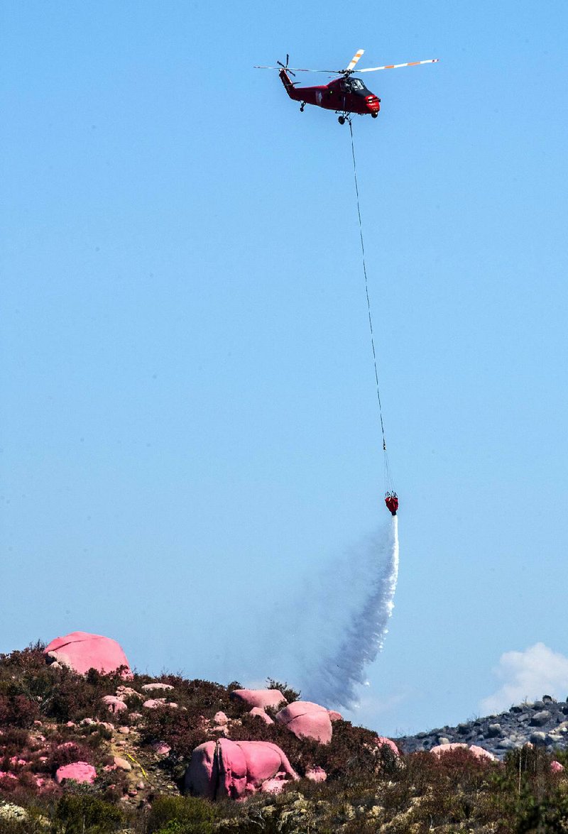 A helicopter drops water Friday on a wildfire in Murrieta, Calif. Evacuation orders in the area were lifted Friday though the fire continues to burn. 