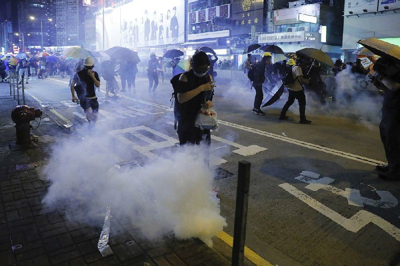 People run for cover from police tear-gas shells Friday during a protest in Hong Kong.