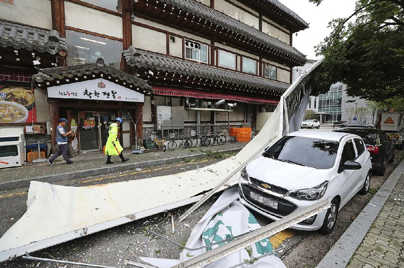 A sign blown off a building by Typhoon Lingling damages a vehicle Saturday in Seoul, South Korea. 