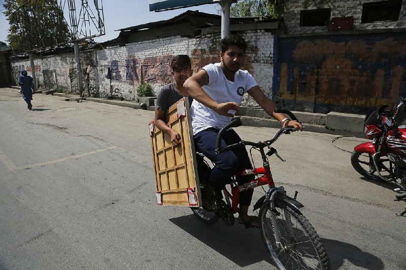 Boys ride in the street last week in Srinagar, in Indian-controlled Kashmir, where a teen shot by security officers during a protest in early August died on Tuesday. 