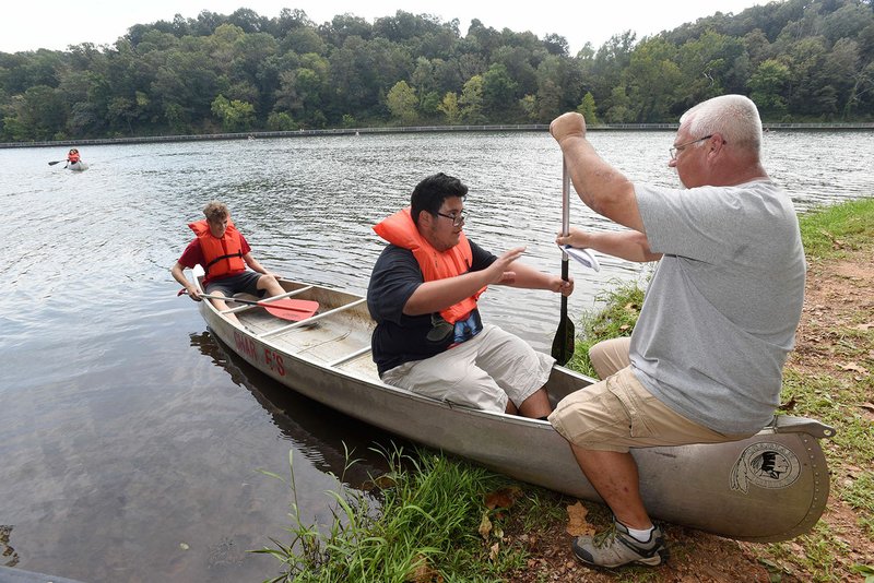 Jay Miles, an outdoor education instructor at Heritage High School in Rogers, gives canoeing tips Tuesday to student Kevin Noguera at Lake Atalanta in Rogers. Outdoor education students learned basic canoeing techniques to prepare them for a trip on the Elk River near Pineville, Mo., next week. NWA Democrat-Gazette/FLIP PUTTHOFF