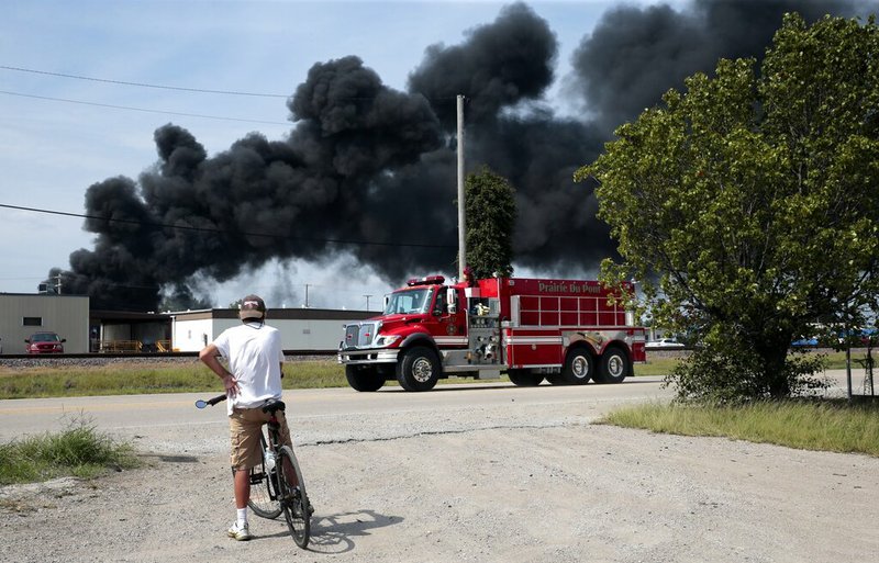 A resident watches as a firetruck arrives in downtown Dupo, Ill. to help fight a tanker fire from a derailed train on Tuesday, Sept. 10. 2019. Black smoke coming from the derailment scene can be seen for miles and caused the evacuation of schools in the town, authorities said. (Robert Cohen/St. Louis Post-Dispatch via AP)