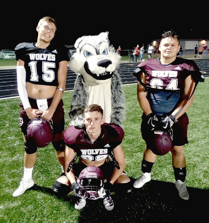 MARK HUMPHREY ENTERPRISE-LEADER Lincoln varsity football players (from left): Tyler Brewer, Blake Arnold and Kris Martinez pose with the Wolves' mascot. Lincoln won its season-opener in nonconference football, 56-7, at Westville, Okla., Friday.