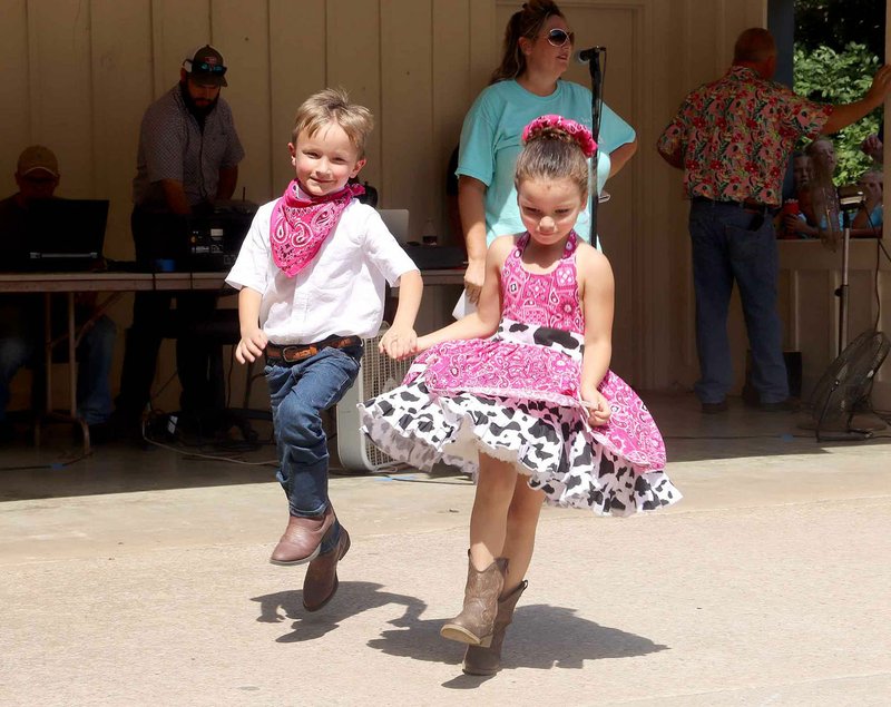 Isabella Contreras and Channing Hunt with Buckles-N-Belles square dance group dance in a circle on the amphitheater stage at the Clothesline Fair.