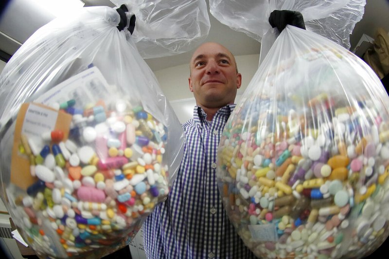 Narcotics detective Ben Hill, with the Barberton Police Department, shows two bags of medications that are are stored in their headquarters and slated for destruction, Wednesday, Sept. 11, 2019, in Barberton, Ohio. Attorneys representing some 2,000 local governments said Wednesday they have agreed to a tentative settlement with OxyContin maker Purdue Pharma over the toll of the nation's opioid crisis. (AP Photo/Keith Srakocic)