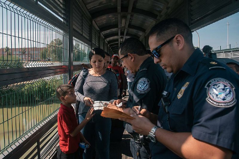 U.S. Customs and Border Patrol officers check the papers of a Venezuelan family seeking asylum on July 10 on the international bridge between Laredo, Texas, and Nuevo Laredo, Mexico. The U.S. Supreme Court ruled Wednesday that the government can begin denying asylum requests from migrants except those who have been denied asylum in another country or are victims of “severe” human trafficking. 