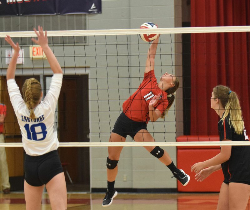 RICK PECK/SPECIAL TO MCDONALD COUNTY PRESS McDonald County's Kaycee Factor goes for a back-row spike while Carthage's Grace Schriever (18) and McDonald County's Sydnie Sanny look on. Carthage won the match, 25-16, 25-21, held on Sept. 3 at MCHS.
