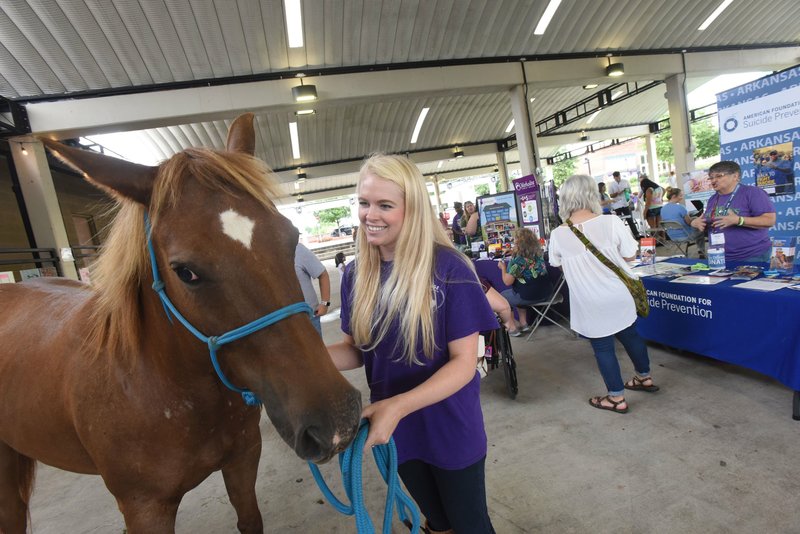 File Photo/FLIP PUTTHOFF Jessie Kersh with Courage Theraputic Riding Center in Prairie Grove shows Rain, one of the center's horses, to MINDfest Northwest Arkansas patrons at the 2018 event.