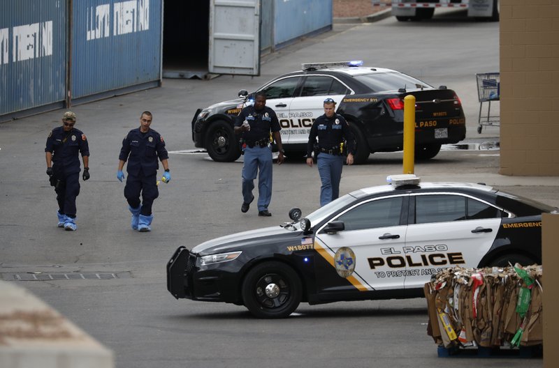 FILE - In this Aug. 6, 2019, file photo, police officers walk behind a Walmart at the scene of a mass shooting at a shopping complex in El Paso, Texas. Patrick Crusius, 21, was indicted Thursday, Sept. 12, 2019, for capital murder in connection with the Aug. 3 mass shooting that left 22 dead. He is jailed without bond. (AP Photo/John Locher, File)