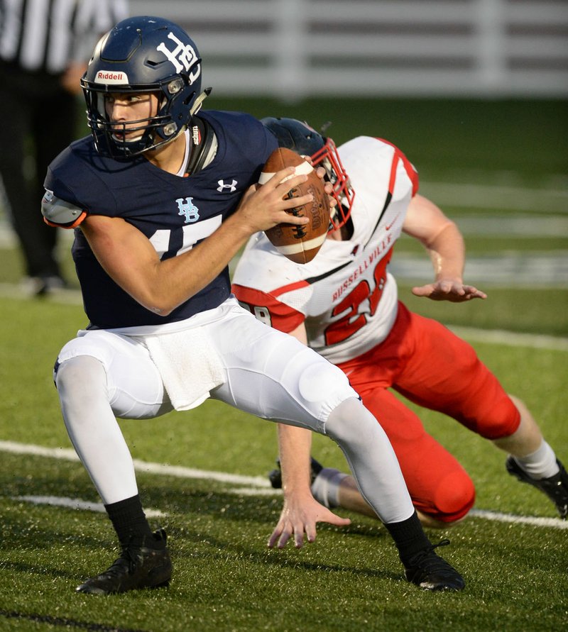 NWA Democrat-Gazette/ANDY SHUPE Springdale Har-Ber quarterback Blaise Wittschen (left) rolls out to pass Friday as he's pursued by Russellville linebacker Ty Toland during the first half at Wildcat Stadium in Springdale. Visit nwadg.com/photos to see more photographs from the game.